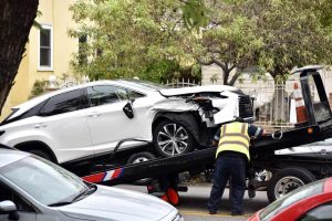 A tow truck driver loading a wrecked car for emergency towing